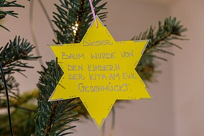Kindergartenkinder schmücken Weihnachtsbaum