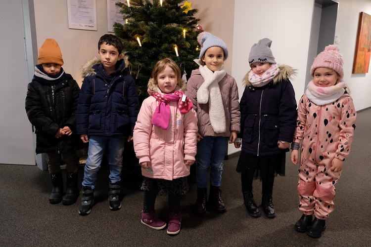 Kindergartenkinder schmücken Weihnachtsbaum